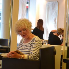 Eine Frau sitzt in einem Friseursalon und liest ein Buch.